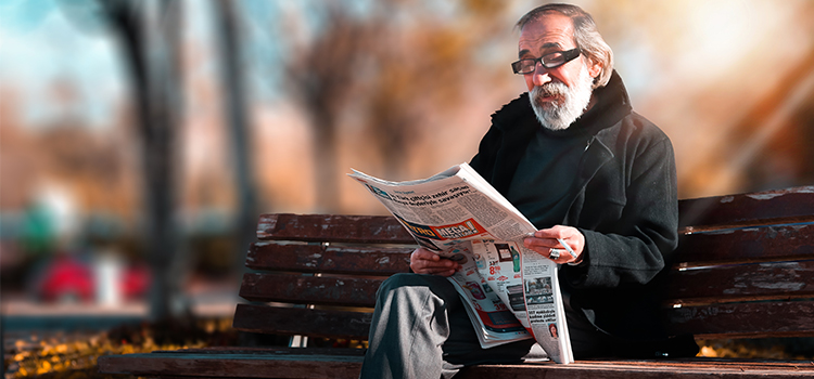 Image d'un vieil homme assis qui lit un journal 